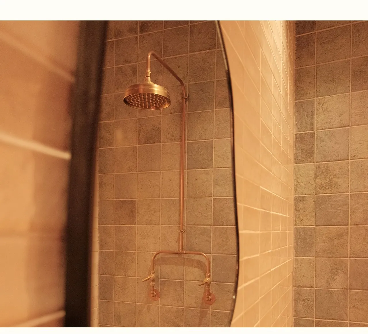 A fabricated brass shower head installed in a tiled wall, hand-finished by Your Neighbourhood Plumber.