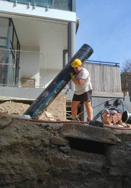 On-site installation work — Avram handling a large pipe section.