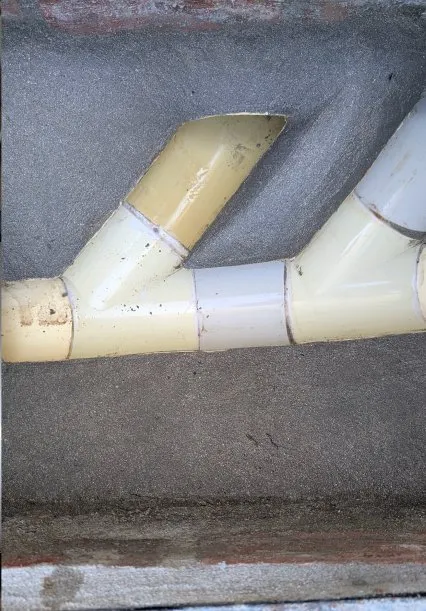 White PVC pipework against a textured wall.