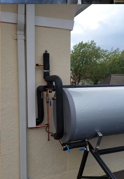 Geyser cylinder installed alongside an outdoor wall.