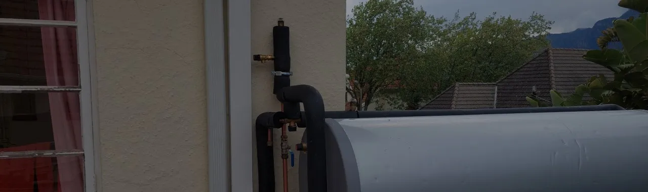 A copper-piped geyser installation, neatly mounted on an exterior wall.
